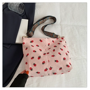 Pink corduroy bucket bag with strawberry print and wide ethnic patterned shoulder strap