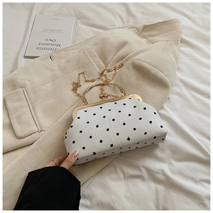 Detailed top view of retro shell bag with black polka dots on white corduroy surface