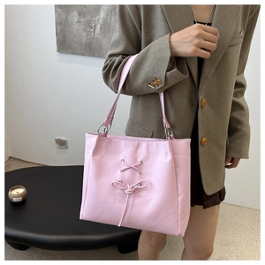 Pink tote bag detail with stylish bow decoration and metallic rings on shoulder straps