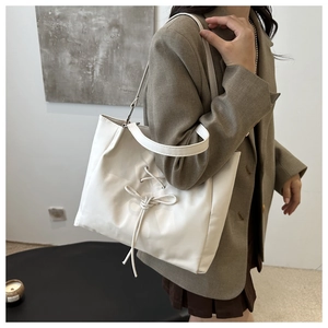 Detail of white tote bag featuring decorative drawstring bow and soft leather texture