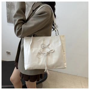 Close-up of a cream-white tote bag featuring stylish drawstring bow details and nylon texture