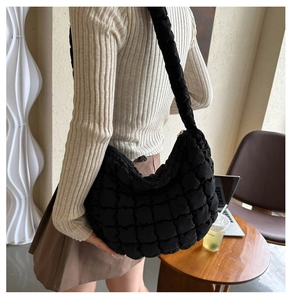 Quilted black puffer hobo bag with textured square pattern worn as a shoulder bag