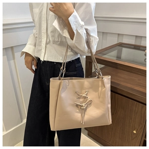 Chic beige tote bag with criss-cross lace details shown in a lifestyle setting