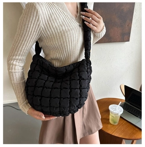 Detailed view of black quilted puffer tote bag on shoulder for daily stylish look
