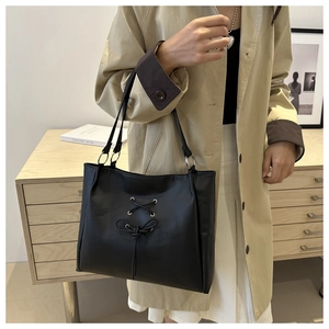 Detailed view of black tote bag with ballet bow design and twisted shoulder straps