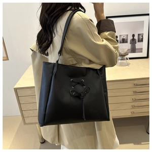Detail of black ballet-style tote bag with bow tie straps and twist shoulder handle