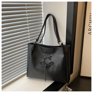 Close-up of black PU leather tote bag featuring stylish cross-lace and bow-tie details