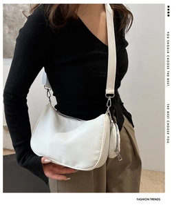 Close-up of white crescent crossbody bag with adjustable strap and detachable coin purse