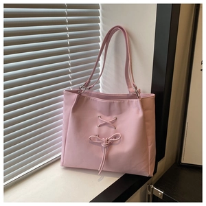 Close-up of pink tote bag featuring a decorative bow and silver metal ring hardware