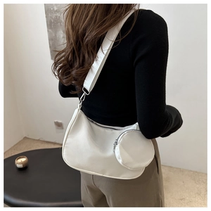 Detailed back view of model wearing white crossbody crescent bag with mini round coin purse