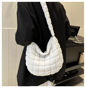 Detailed close-up of a white quilted puffer tote bag worn over a black suit blazer