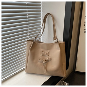 Detail of light khaki tote bag featuring elegant bow tie and metal ring strap connectors