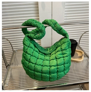 Close-up of bright green puffy quilted tote bag with metallic zipper and handle texture