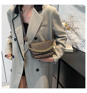 Brown monogram crossbody bag featuring a golden chain strap and wide patterned shoulder strap