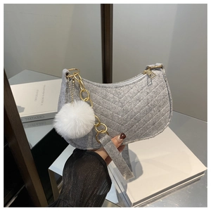Detail of grey felt crescent bag with V-quilting, gold chain, and white fur pompom charm