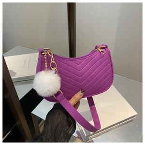 Detail of purple chevron-stitched hobo bag with gold hardware and white pompom charm