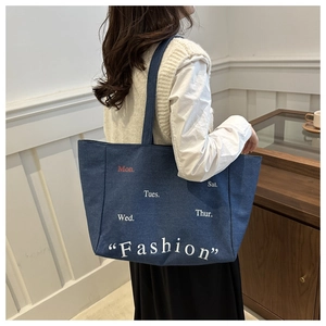 Detail of blue denim tote bag with fashion lettering and white weekday prints