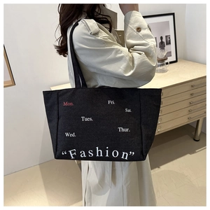 Detail of black canvas tote bag with fashion print and weekdays letters in white and red