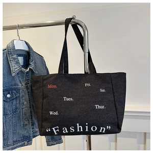 Detail of black canvas tote bag with fashion print and embroidered weekly lettering