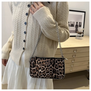 Detail of leopard print shoulder bag with silver studs and chain strap on a model
