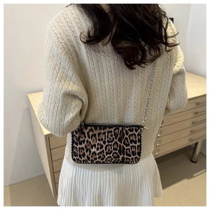 Close-up of leopard print shoulder bag with silver chain strap on a model's shoulder