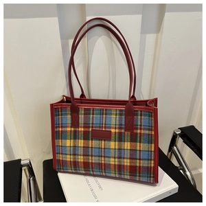 Close-up of tartan canvas tote bag with red leather trim and long shoulder handles
