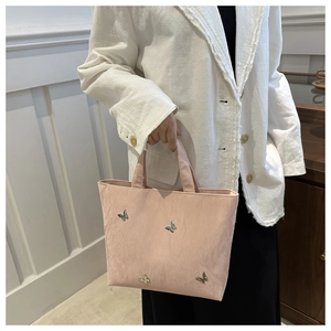 Detail van roze shopper met zilveren metalen vlinders op getextureerde stof