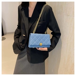Light blue quilted denim square crossbody bag with gold chain strap shown on a model