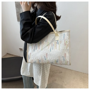Détail d'un grand sac cabas avec broderie rayée montrant la texture sur le mannequin
