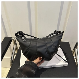 Detailed view of the pleated black leather dumpling bag with metal zipper and fine stitching