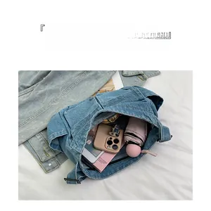 Detail of denim crossbody bag showing spacious interior with phone, umbrella and notebook