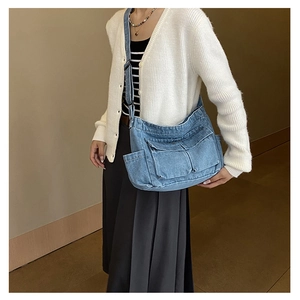 Detail of blue denim shoulder bag featuring multi-pocket design and adjustable strap