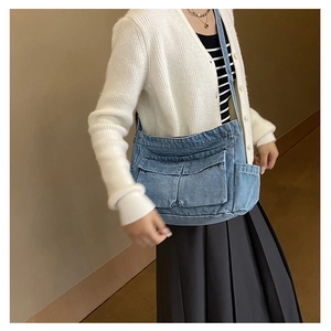 Detail of blue denim crossbody bag with multi-pocket utility design and shoulder strap