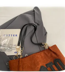 Detail of brown suede tote bag with black handles, gold chain and chic patches