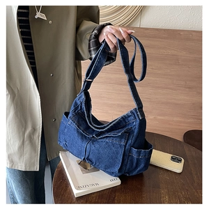 Detail of blue denim tote bag featuring functional front cargo pockets and contrast stitching