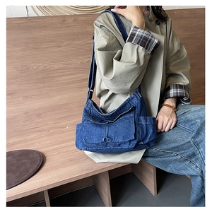 Detail of deep blue denim crossbody bag with functional side pockets and adjustable strap