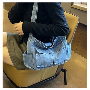 Detail of blue denim tote bag with functional pockets and wide strap on model