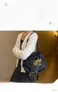 Detail of vintage washed denim tote featuring yellow embroidery and a pearl chain strap