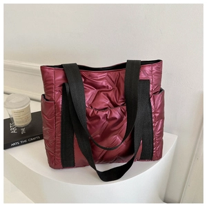 Close-up of wine red quilted tote bag with padded nylon texture and side pocket