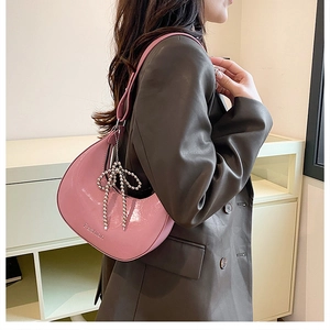 Close-up of pink crescent dumpling bag with pearl bow charm and Fashion stamp