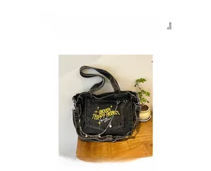 Detail of vintage washed denim tote bag in black with yellow embroidery and pearl chain