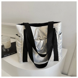Detail of silver quilted tote bag with metallic finish and black nylon shoulder straps