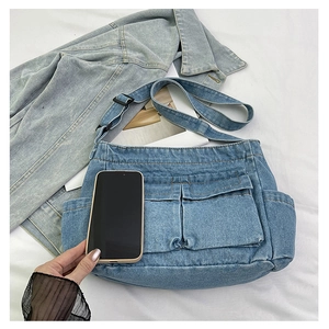 Detail of denim crossbody bag featuring utility pockets and adjustable nylon shoulder strap