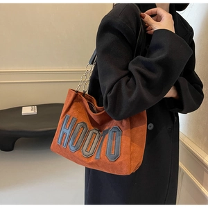 Close-up of caramel brown matte tote bag featuring embroidered HOO10 letters and chain strap