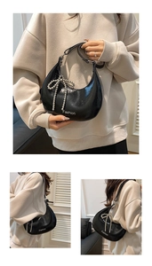 Close-up of black patent leather half-moon bag with bow charm and Fashion logo