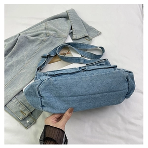Close-up of quilted denim shoulder bag showing puffy texture and wide strap detail