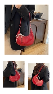 Detail view of red glossy crescent bag with white pearl bow and Fashion typography