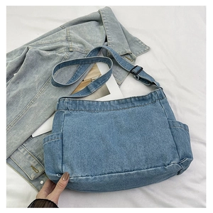Detail of light blue denim tote bag featuring adjustable shoulder strap and side pockets