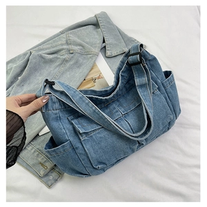 Detailed view of dark blue denim tote bag with functional pockets and adjustable strap