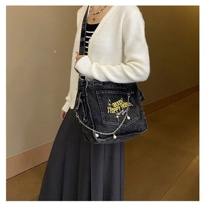 Detail of black denim crossbody bag with yellow groovy trippy heart embroidery and silver chain